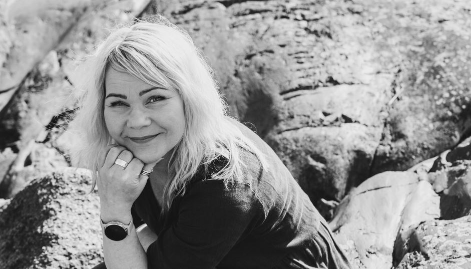 Irene Etäsalo hymyilee kameralle, taustalla kalliota.