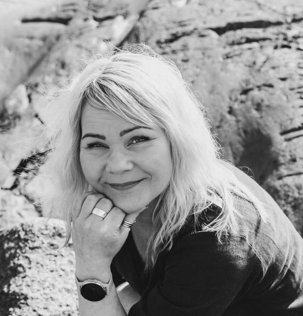 Terapia ja työnohjauspalveluita tarjoava Irene Etäsalo hymyilee kameralle, taustalla kalliota.