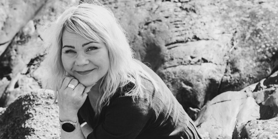 Irene Etäsalo hymyilee kameralle, taustalla kalliota.