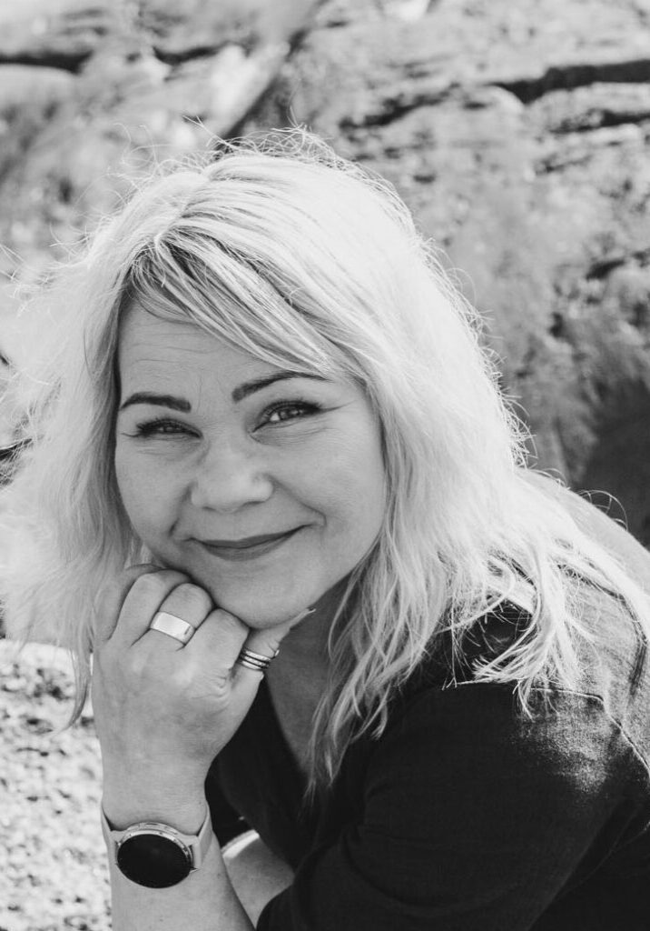 Terapia ja työnohjauspalveluita tarjoava Irene Etäsalo hymyilee kameralle, taustalla kalliota.