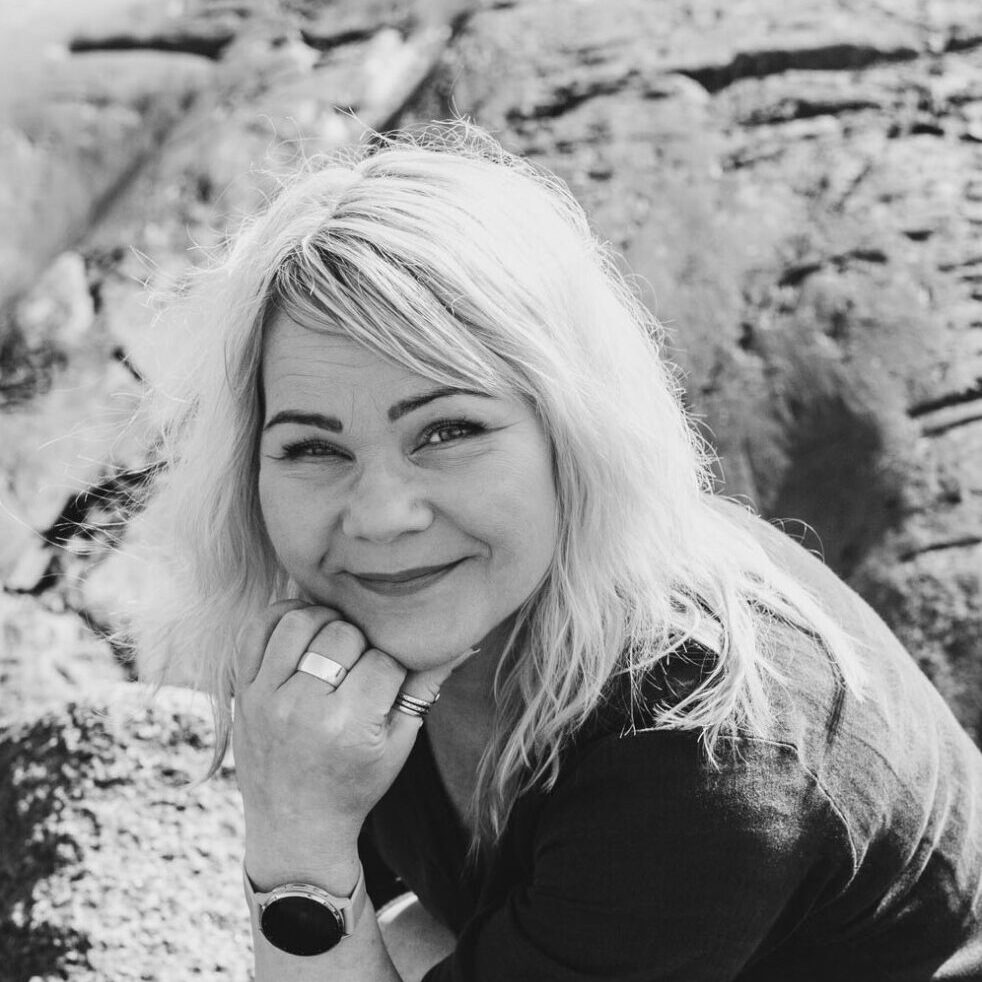 Terapia ja työnohjauspalveluita tarjoava Irene Etäsalo hymyilee kameralle, taustalla kalliota.