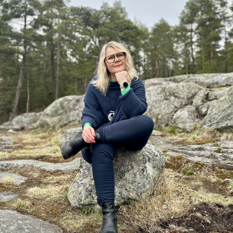 Työnohjaaja Irene Etäsalo istuu kalliolla